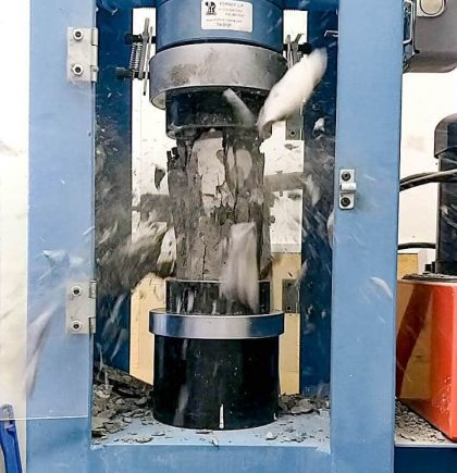 A technician breaking a concrete cylinder to test its strength